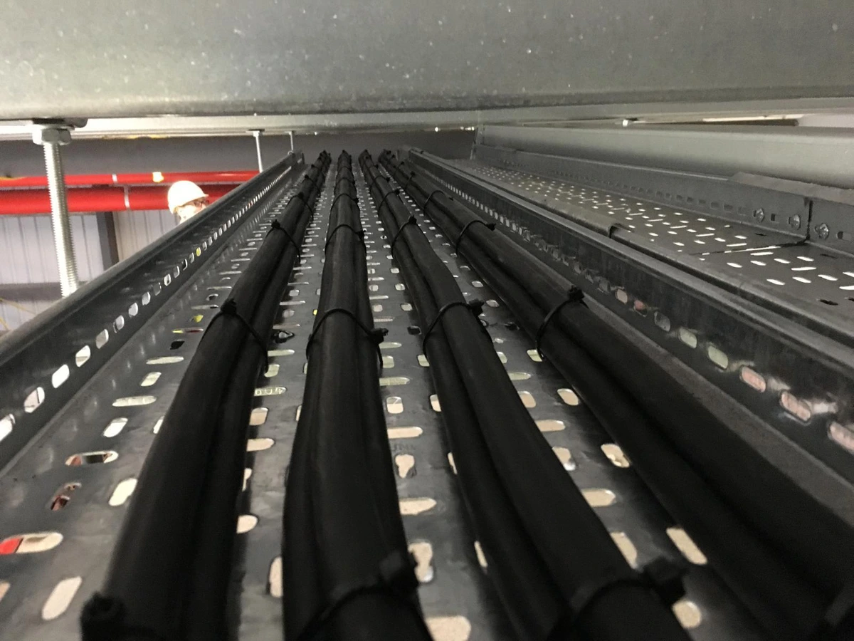 Four runs of black cable laid and tied on a galvanised cable tray