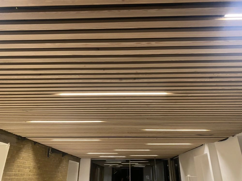Slatted timber ceiling with recessed linear LED lighting in a commercial interior