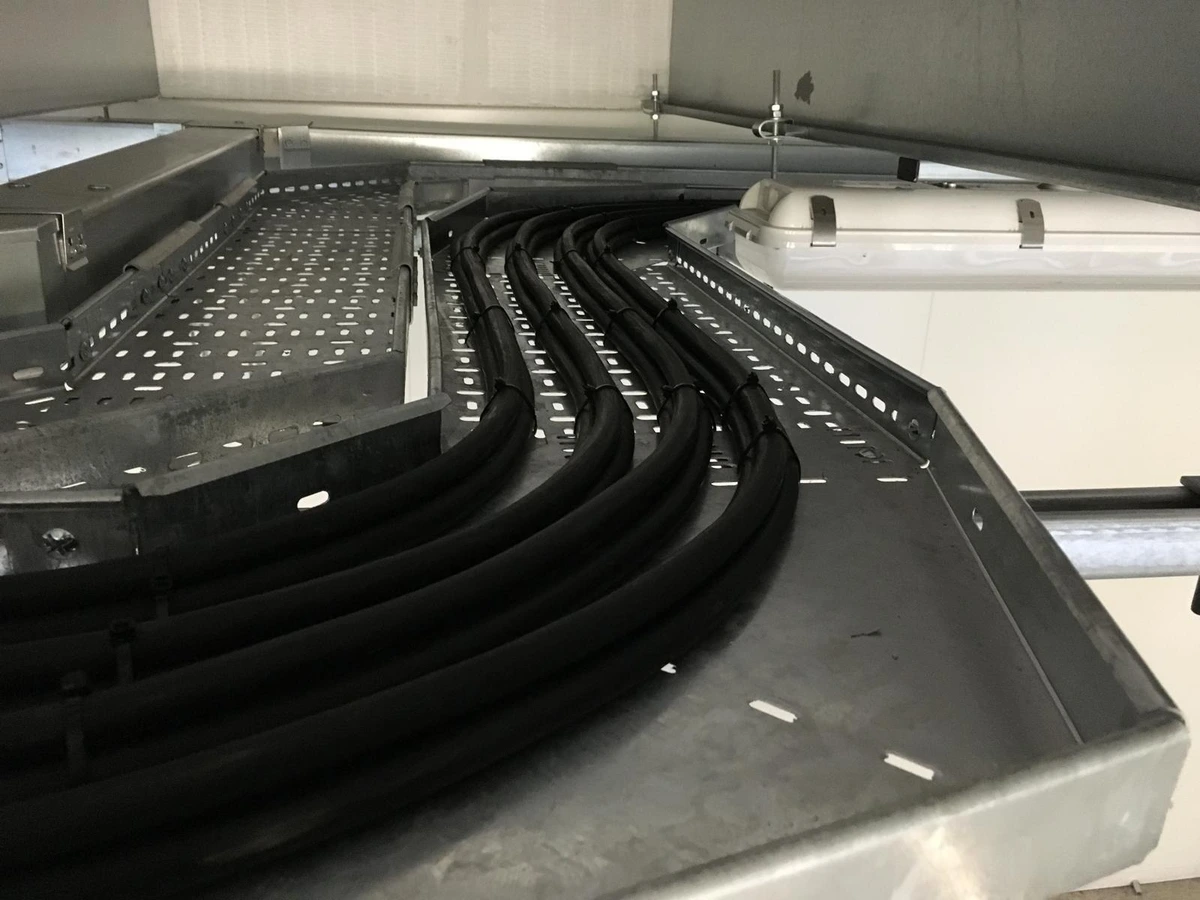Black cables routed in curves along a galvanised cable tray